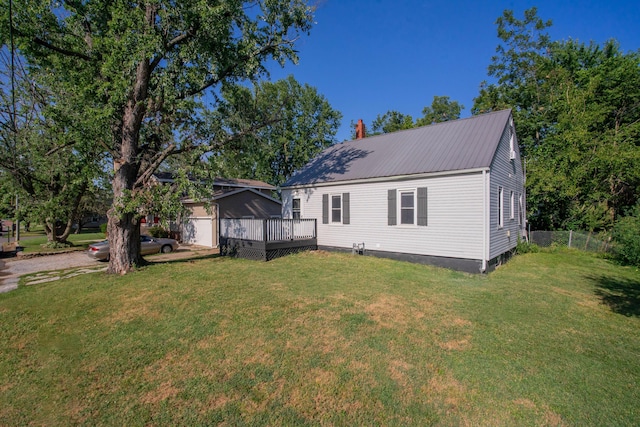 rear view of house with a lawn, fence, a deck, and metal roof