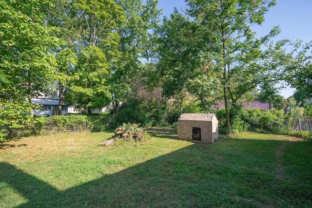 view of yard featuring fence, a storage unit, and an outbuilding