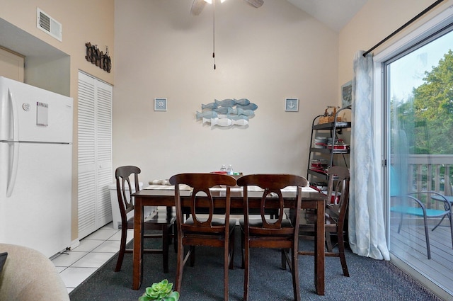 tiled dining space with high vaulted ceiling and ceiling fan