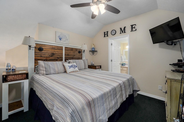 bedroom with ceiling fan, vaulted ceiling, ensuite bathroom, and dark colored carpet