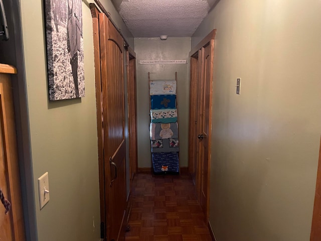 hallway featuring dark parquet flooring and a textured ceiling