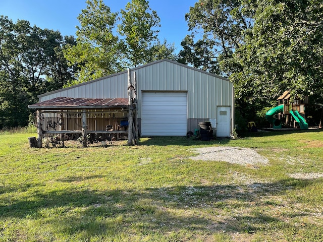 view of outbuilding featuring a playground, a lawn, and a garage