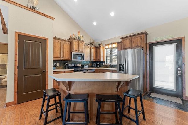 kitchen with a breakfast bar area, appliances with stainless steel finishes, a kitchen island, and light wood-type flooring