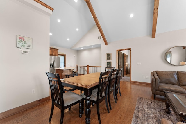 dining area featuring light wood-type flooring, beam ceiling, and high vaulted ceiling