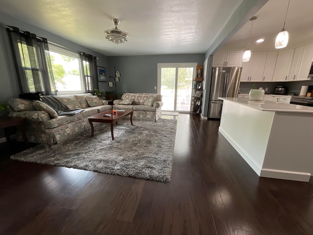 living room with dark hardwood / wood-style flooring, a wealth of natural light, and a chandelier