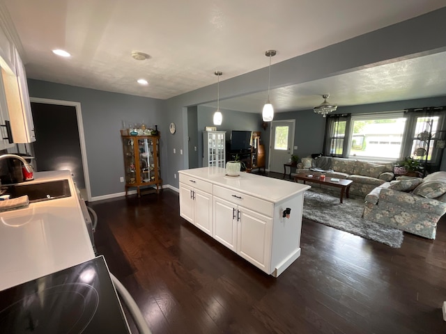 kitchen with dark wood-type flooring, sink, white cabinets, a center island, and hanging light fixtures