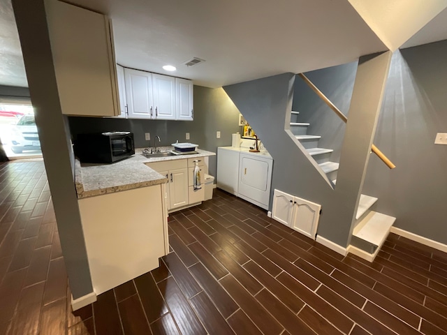 kitchen featuring dark hardwood / wood-style flooring, white cabinets, washer and dryer, and sink