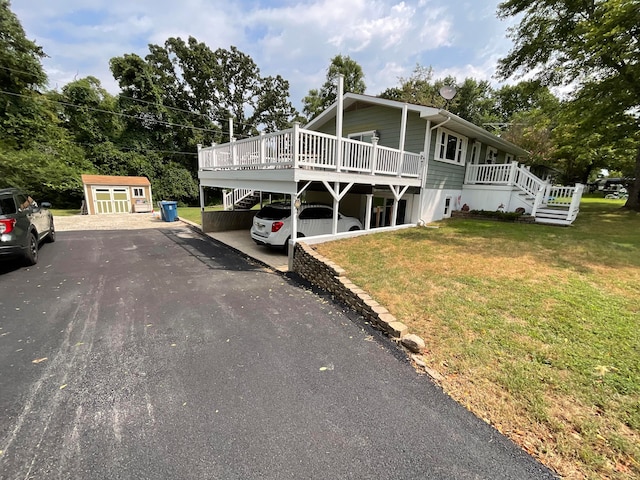 view of front of property featuring a front lawn, a deck, and a storage unit