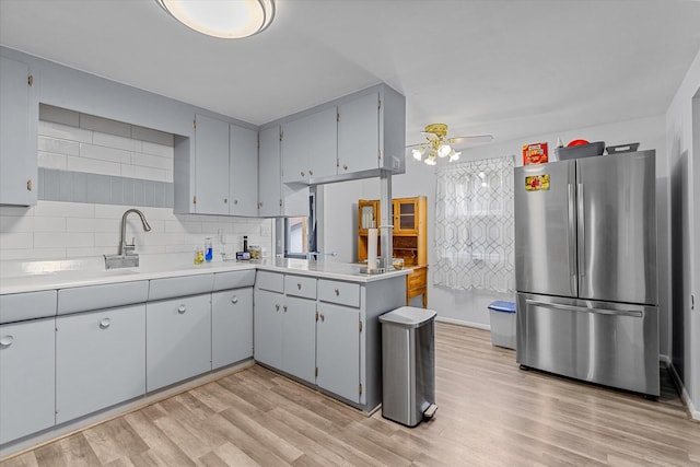 kitchen with stainless steel refrigerator, light hardwood / wood-style floors, kitchen peninsula, and decorative backsplash