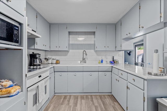 kitchen with kitchen peninsula, tasteful backsplash, oven, gas cooktop, and light wood-type flooring