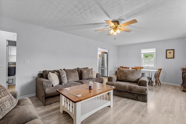 living room featuring a textured ceiling, ceiling fan, and light hardwood / wood-style flooring