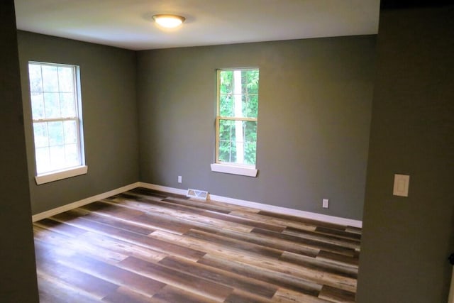 unfurnished room featuring baseboards, wood finished floors, and visible vents