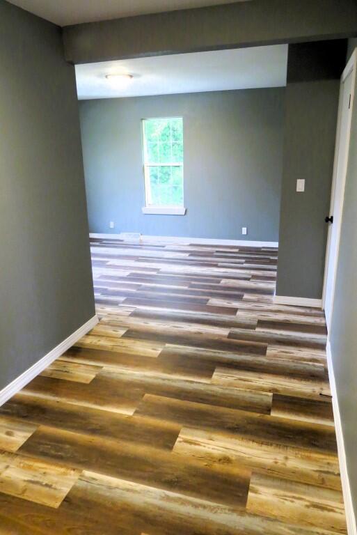 spare room with baseboards and wood finished floors