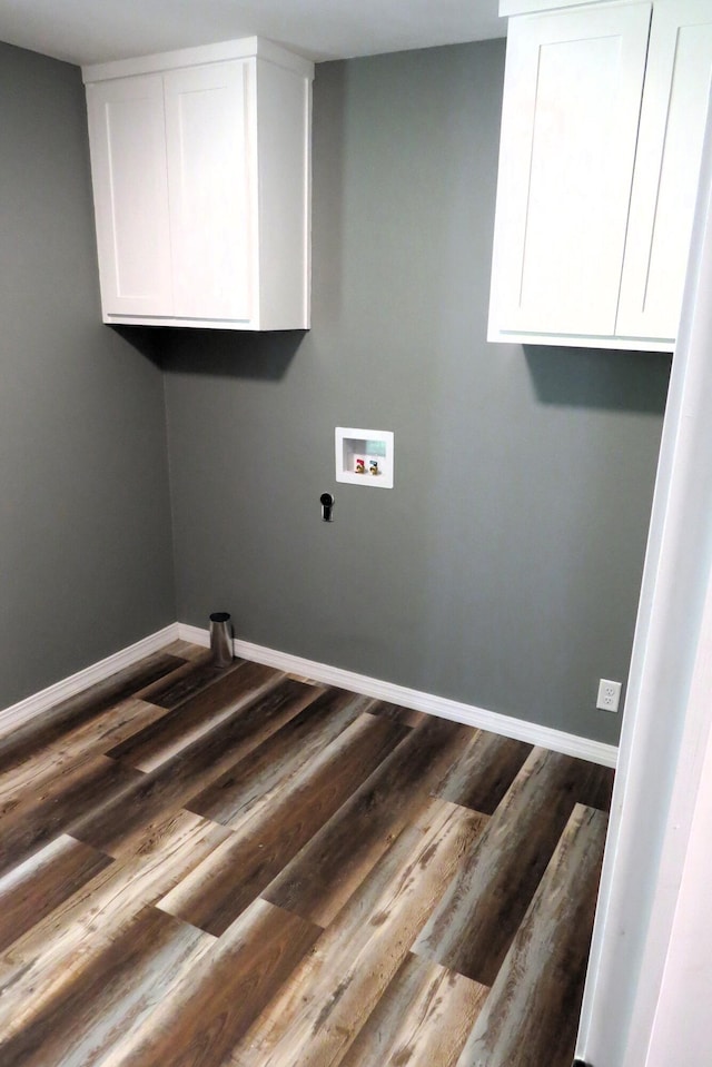 washroom featuring baseboards, cabinet space, dark wood-type flooring, and washer hookup