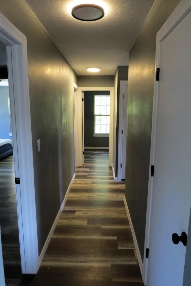 hall featuring a textured ceiling and dark hardwood / wood-style flooring