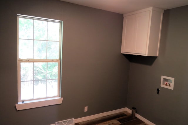 clothes washing area with wood finished floors, hookup for a washing machine, cabinet space, baseboards, and visible vents