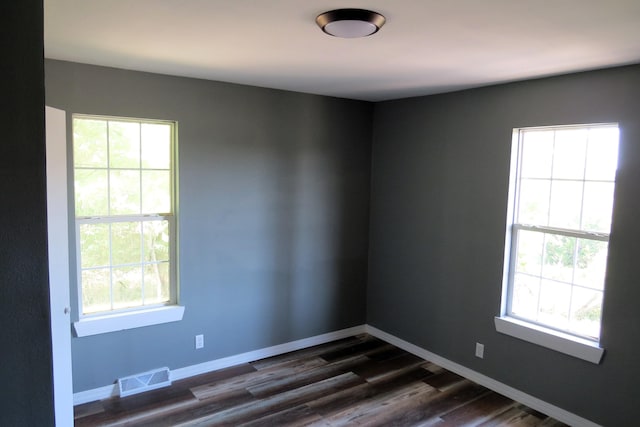 unfurnished room featuring plenty of natural light and dark hardwood / wood-style floors