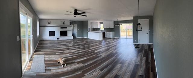 unfurnished living room featuring a ceiling fan and dark wood-style floors