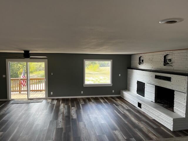 unfurnished living room with baseboards, a fireplace, and dark wood-style floors