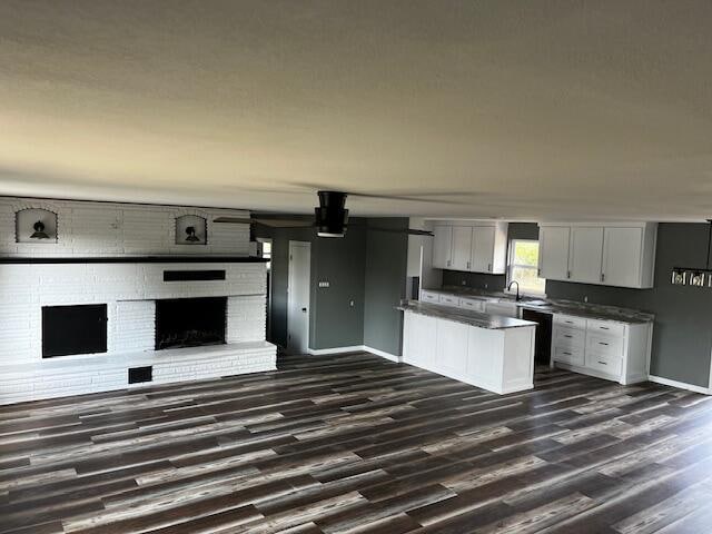 kitchen with a brick fireplace, dark hardwood / wood-style floors, sink, and white cabinetry