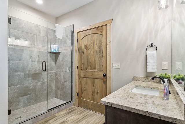 bathroom with a shower with door, hardwood / wood-style flooring, and vanity