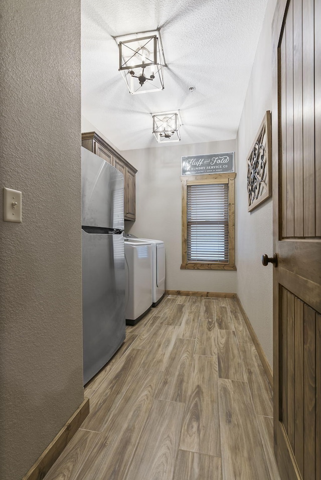 laundry area with cabinets, a textured ceiling, light hardwood / wood-style floors, and washer and dryer