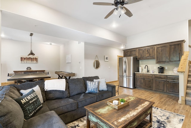 living room featuring sink, light hardwood / wood-style flooring, and ceiling fan