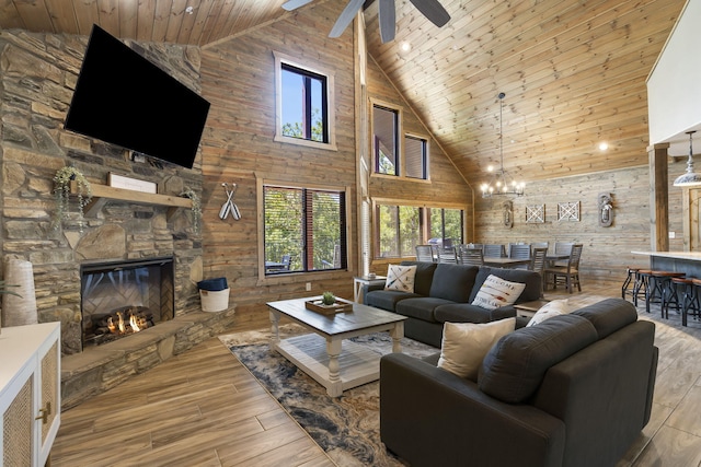 living room featuring wood walls, light hardwood / wood-style floors, wooden ceiling, a fireplace, and high vaulted ceiling