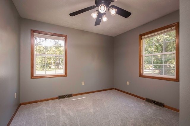 carpeted empty room with a wealth of natural light and ceiling fan