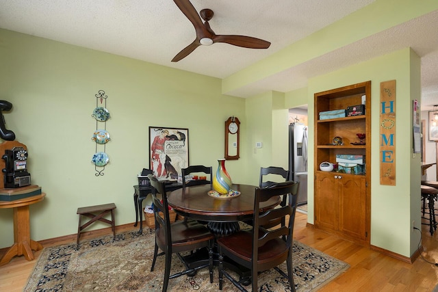 dining room featuring ceiling fan, baseboards, light wood-style floors, and a textured ceiling
