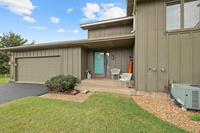 entrance to property with cooling unit, an attached garage, a lawn, board and batten siding, and aphalt driveway