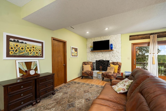 living area with a textured ceiling, visible vents, recessed lighting, wood finished floors, and a fireplace