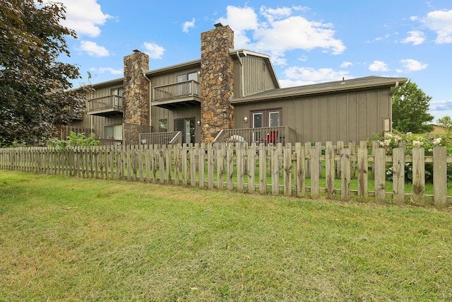 rear view of property featuring fence private yard, french doors, a lawn, and a balcony