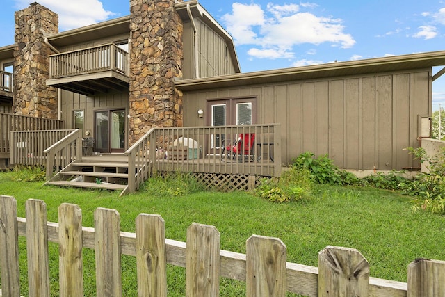 back of house with a wooden deck, a balcony, a yard, and board and batten siding