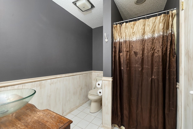 bathroom featuring lofted ceiling, sink, tile patterned floors, toilet, and a textured ceiling