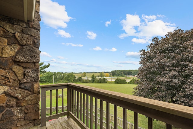 wooden terrace featuring a yard and a rural view