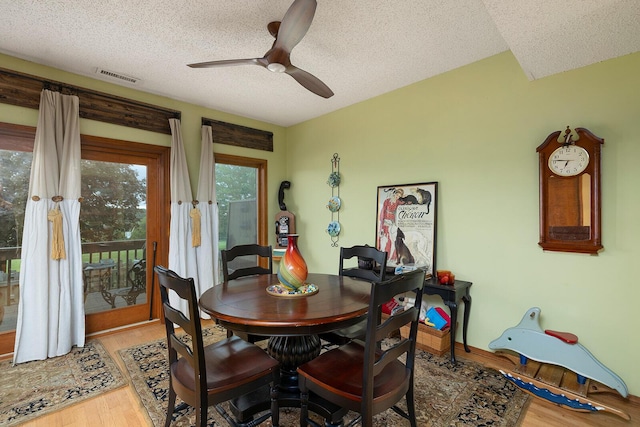 dining space with light wood finished floors, visible vents, a textured ceiling, and ceiling fan