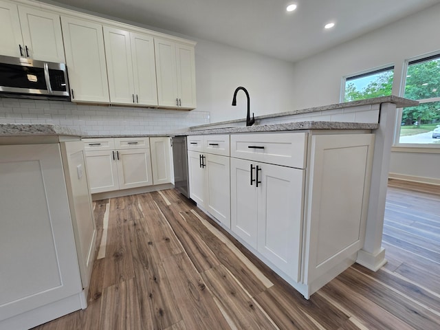 kitchen featuring decorative backsplash, light hardwood / wood-style floors, and white cabinets