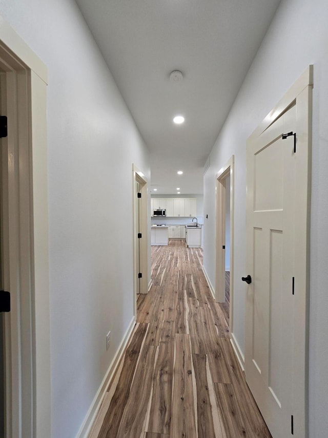 corridor with light hardwood / wood-style floors and sink