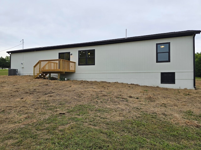 back of property with a wooden deck, a lawn, and central AC unit