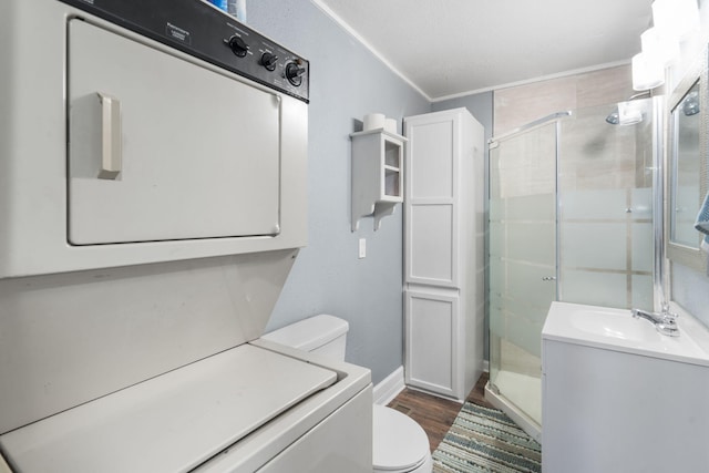 bathroom with stacked washing maching and dryer, a shower with shower door, wood-type flooring, vanity, and toilet