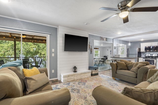 living room with ceiling fan, a textured ceiling, and light hardwood / wood-style floors