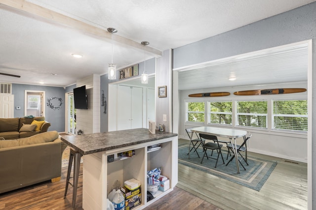 kitchen with decorative light fixtures, a breakfast bar area, dark hardwood / wood-style flooring, kitchen peninsula, and a textured ceiling