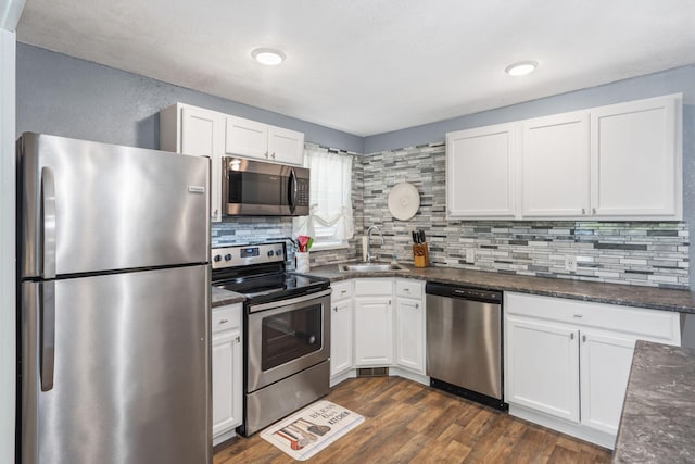 kitchen with stainless steel appliances, sink, dark stone countertops, and white cabinets