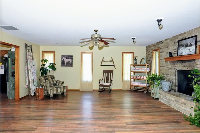 living area featuring a fireplace, dark hardwood / wood-style flooring, and ceiling fan