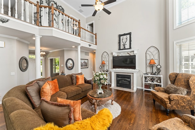 living room with ornate columns, plenty of natural light, a towering ceiling, and dark hardwood / wood-style floors