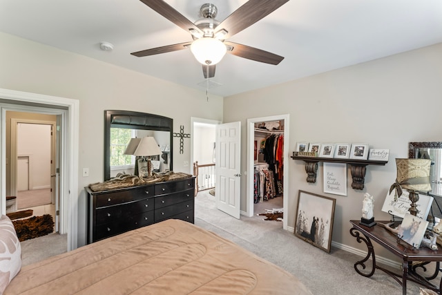 bedroom with light carpet, a closet, a walk in closet, and ceiling fan