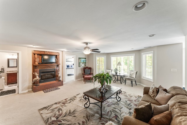 carpeted living room featuring a brick fireplace, a textured ceiling, and ceiling fan