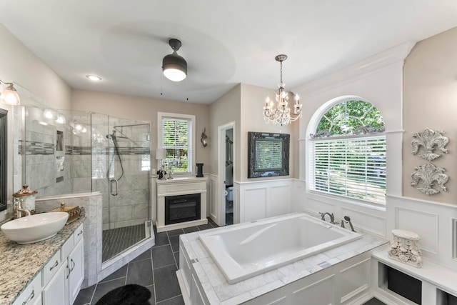 bathroom featuring ceiling fan with notable chandelier, tile patterned floors, separate shower and tub, and vanity