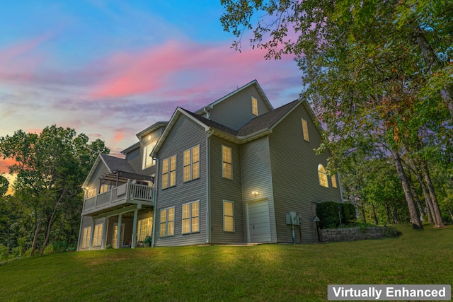 property exterior at dusk featuring a balcony and a lawn